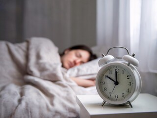 Woman Sleeping Peacefully in Bed With Alarm Clock Nearby at Early Morning