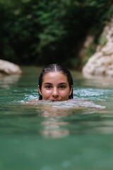 Fototapeta premium A woman is swimming in a pool. She is wearing a swimsuit and has long hair. The water is clear and calm