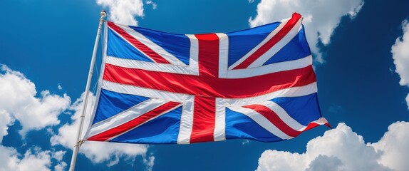 A vibrant Union Jack flag waving in a clear blue sky adorned with fluffy clouds.