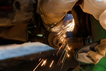 Mechanic Grinding Metal with Sparks in Automotive Workshop