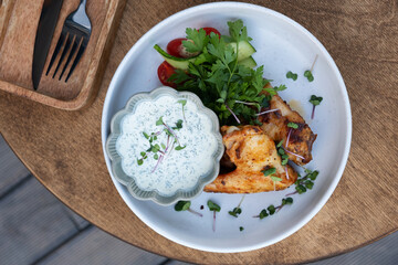 Delicious fried chicken wings with yogurt sauce and greens top view
