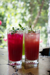 Colored summer lemonades with ice and mint on wooden cafe table
