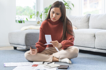 Business financial concept, stressed asian young woman hand checking list with bill for calculate...