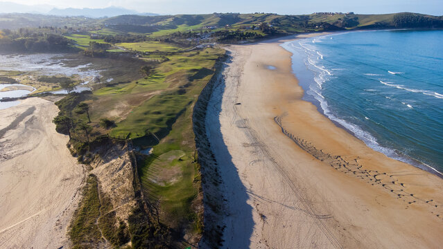 Sandy La Rabia beach, green hills, and misty mountains. Cantabria, Spain.