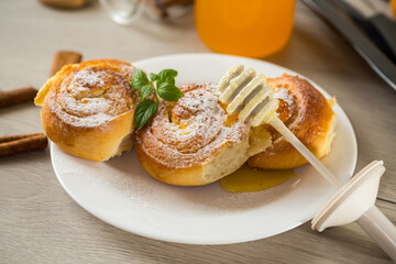 Pastries. Sweet buns with cottage cheese filling and honey in a plate on a wooden table