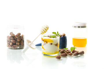 homemade yogurt with kiwi, honey and nuts in a glass, isolated on white background