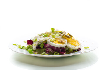 Light salad with egg in a plate, isolated on white background