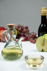 Apple cider vinegar in a vinegar cruet with spout on the background of fruits.