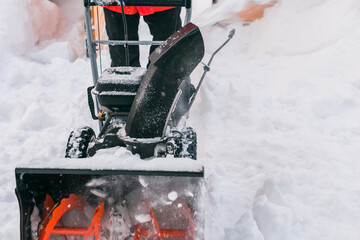 Closeup of red snow blower in action. Senior mature man outdoor in front of house using snowblower...