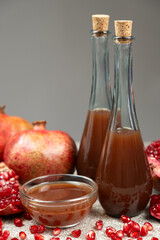 Pomegranate vinegar in a glass bottles among pomegranates.