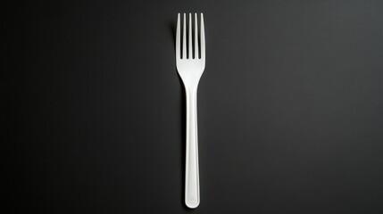 Disposable white plastic fork on a black background with ample empty space for text or design elements in advertising or marketing.
