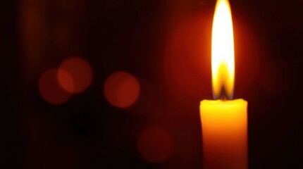 Single Bright Candle Flame Illuminating Dark Background with Bokeh