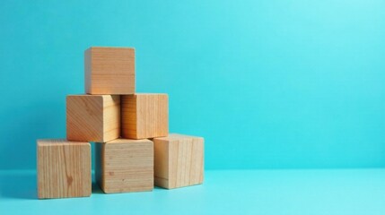Obraz premium Simple Wooden Blocks Arranged in a Pyramid Shape Against a Light Blue Background
