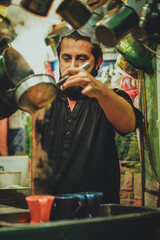 Young Pakistani Afghani Pathan man street vendor pouring chai tea into cups