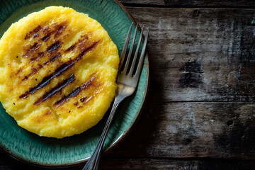 Grilled Polenta Slice with Fresh Herbs and Olive Oil on Green Plate