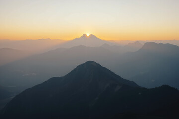 Mountain peak at dawn with sunrise and misty valleys