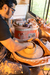 A skilled craftsman shaping beautiful pottery on a spinning wheel in a bright, creative studio