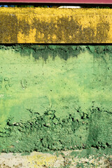 Muro de hormigón deteriorado pintado de verde y amarillo