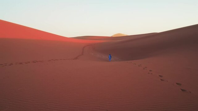nomadic arab man walking in sand dune landscape in desert in north africa