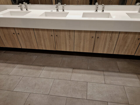 stylish washing corner. stainless steel soap dispenser and paper towel dispenser. white corian furniture sink, wash basin, lever tap. wastebasket in the counter, brown, lock