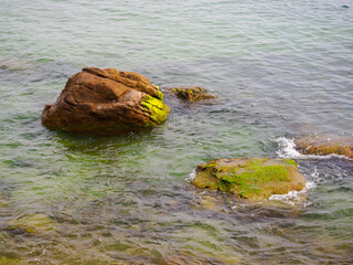 Rocks in the sea crashing against soft waves