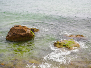 Rocks in the sea crashing against soft waves
