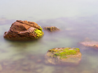 Rocks in the sea crashing against soft waves