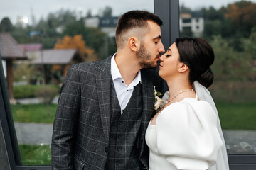 the couple is probably at a wedding. The woman is wearing a long-sleeved white dress with a veil, and the man is wearing a gray checkered suit with a white shirt.