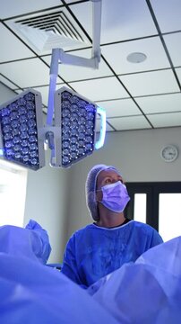 Surgeon standing at the legs of the patient looks aside up at the monitor. Specialist performs gynecologic operation in modern hospital. Vertical video.