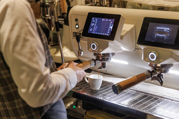 The waiter is using a coffee machine to make coffee