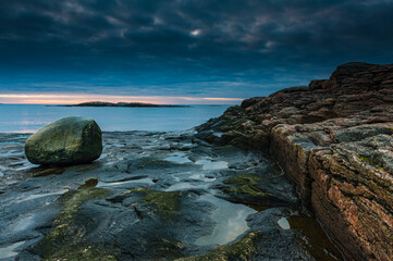 Seascape in Sweden captures serene rocky coastline at dusk with tranquil water and moody sky