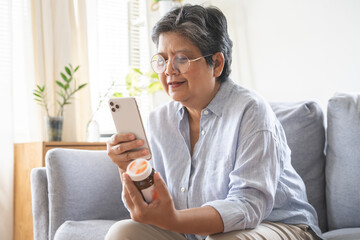 Health care concept, asian senior woman using smart phone reading, searching prescription on bottle...
