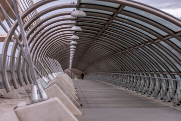 A beautifully designed curved pedestrian bridge showcasing modern architectural design, inviting individuals to traverse urban landscapes with grace and fluidity.