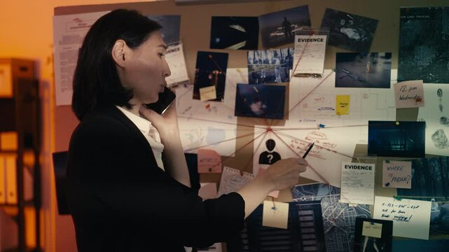 Asian woman detective talks on phone with a colleague, working on a case