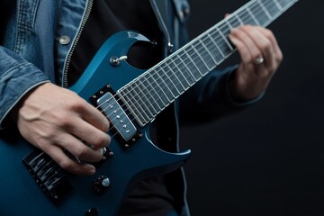 Fototapeta premium Skilled musician performs with electric guitar wearing denim jacket against dark background