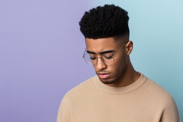 Obraz premium Pensive Young Man with Glasses Against a Two-Tone Background