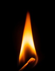 close-up of a glowing matchstick flame with bright orange hues and a dark background
