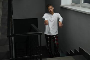 Young man suffering from sleepwalking on stairs indoors, space for text