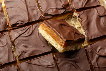 Caramel shortbread, also known as caramel squares, slice, or millionaire's shortbread. Dessert, cake made with  shortbread biscuit base topped with caramel and chocolate. Food background.