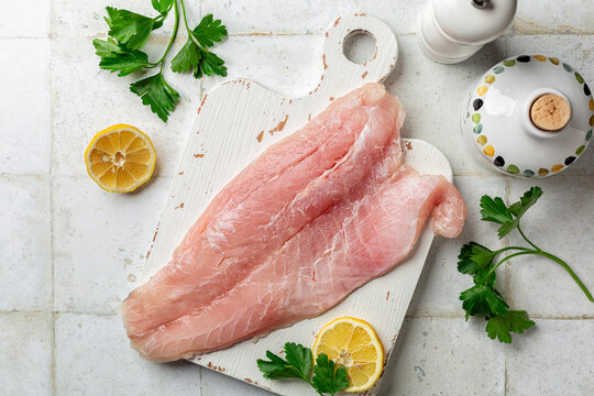 Nile Perch Fillet, raw fish, ready to be cooked on a white board.