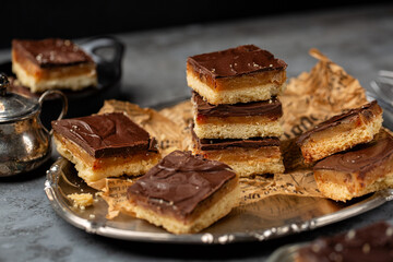 Caramel shortbread, also known as caramel squares, slice, or millionaire's shortbread. Dessert, cake made with shortbread biscuit base topped with caramel and chocolate. Homemade.