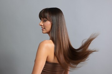 Naklejka premium Hair styling. Beautiful woman with straight long hair on grey background