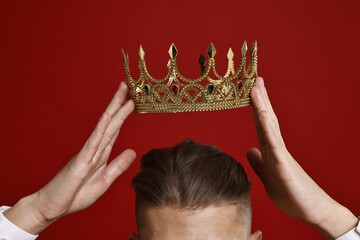 Man wearing luxury crown on red background, closeup