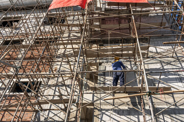 Back view worker standing on bamboo scaffolding working on height building at site