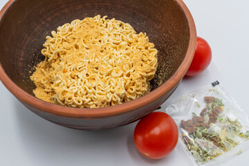 Instant pasta with herbs and spices in a bowl on a white background.