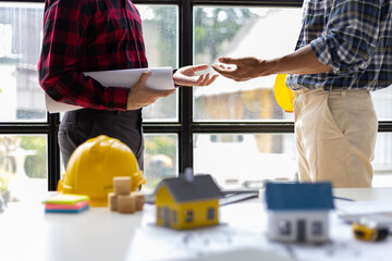 Architect colleague in the office is talking with a contractor and discussing the correct planning...