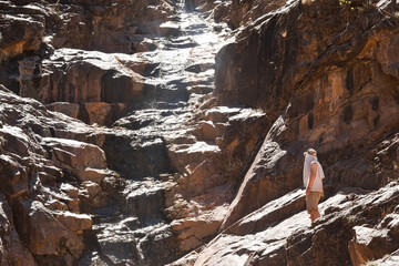 Person looking up at a rocky waterfall on a hike 