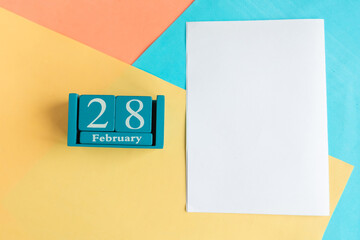 February 28. Blue cube calendar with month and date and white mockup blank on color geometric...