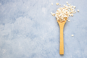 Oat flakes with wooden spoon on blue background
