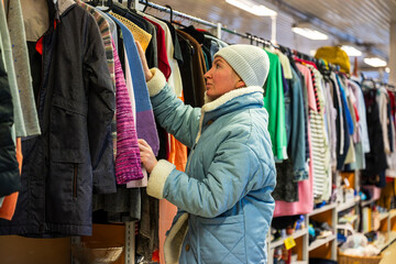 Woman browsing clothes in a thrift shop. Second hand concept